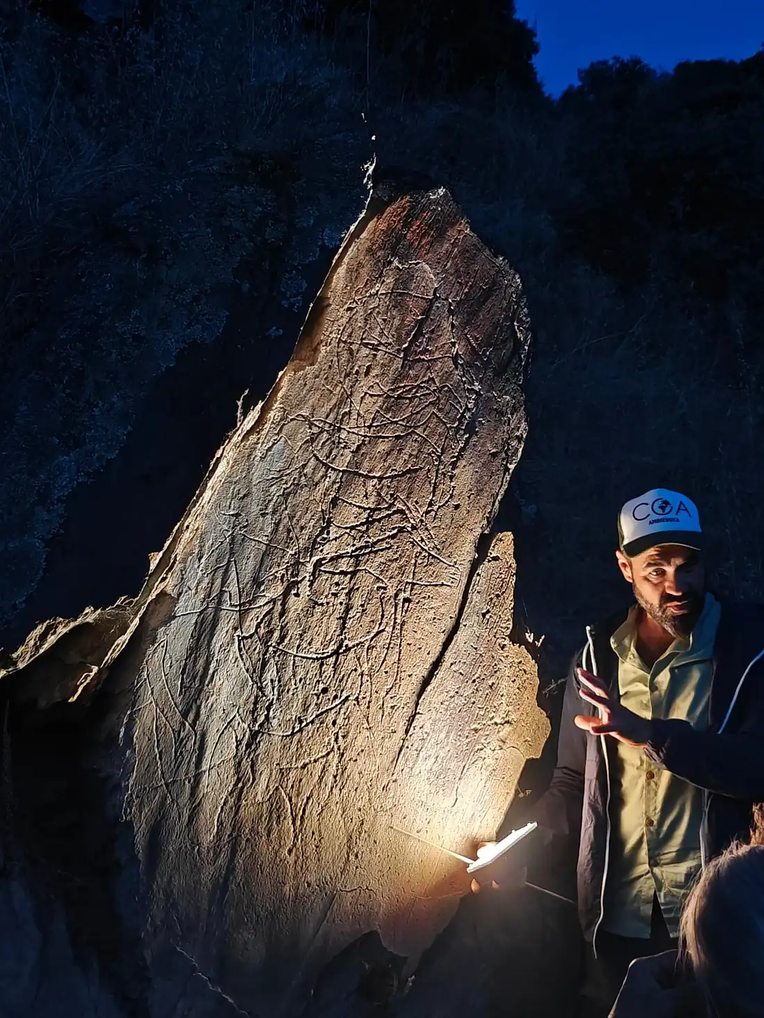 Engraved rock illuminated by lantern light on a night visit